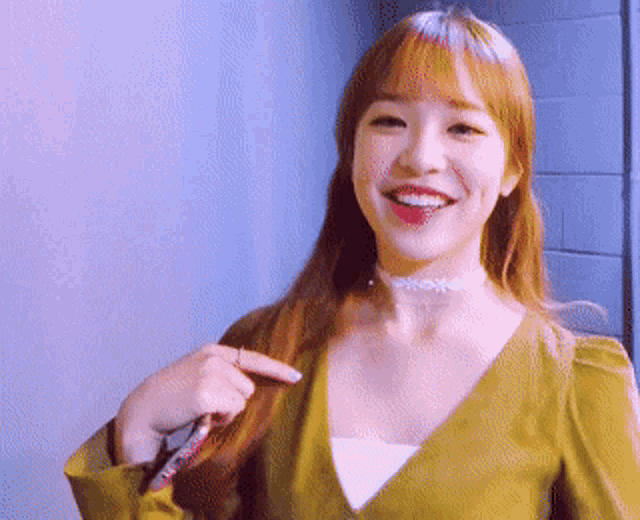 a woman wearing a choker and a yellow top is smiling