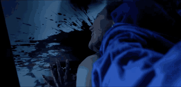 a man in a blue shirt is looking at a bloody screen