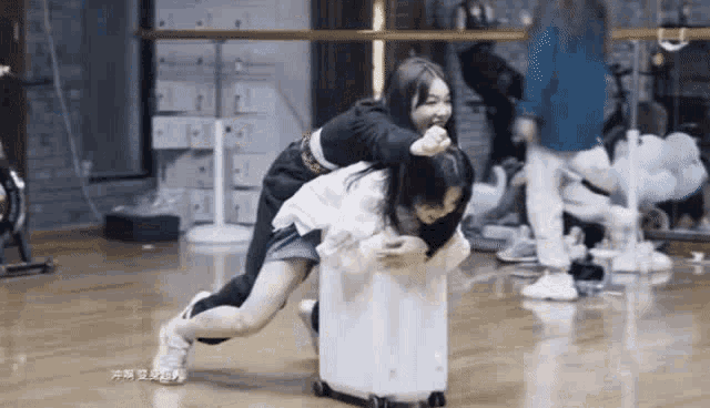 two girls are playing with a white suitcase in a room .