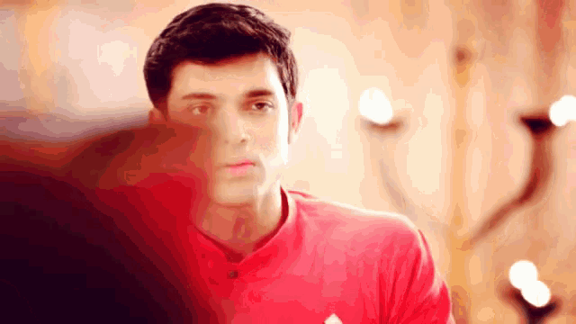 a man in a red shirt is standing in front of a candle holder .