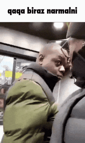 a man in a green jacket is talking to another man in a black hat