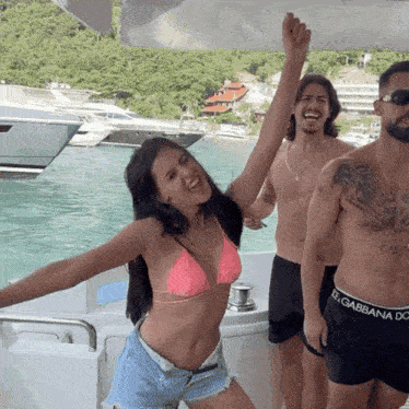 a woman in a pink bikini stands on a boat