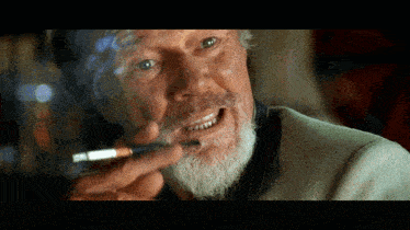 a man with a beard is smoking a cigarette and smiling