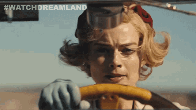 a woman driving a car with #watchdreamland written on the screen