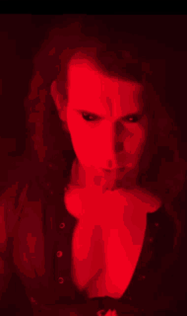 a woman 's face is lit up in red and her breast is visible
