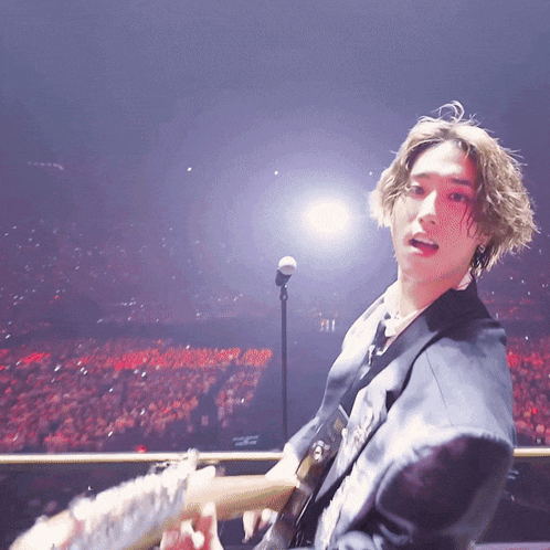 a man playing a guitar in front of a microphone