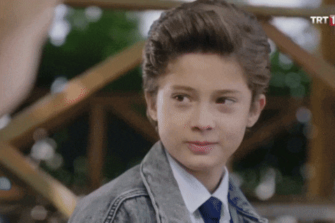 a young boy in a denim jacket and tie looks at the camera with a trt logo in the corner