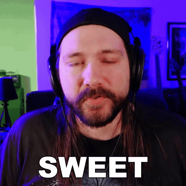 a man with long hair and a beard is wearing headphones and says sweet
