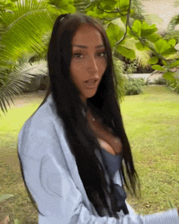 a woman with long black hair is standing in a grassy field .