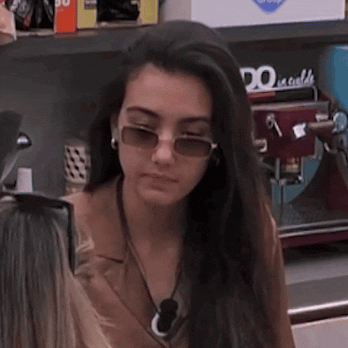 a woman wearing sunglasses is standing in front of a machine that says ' do ' on it