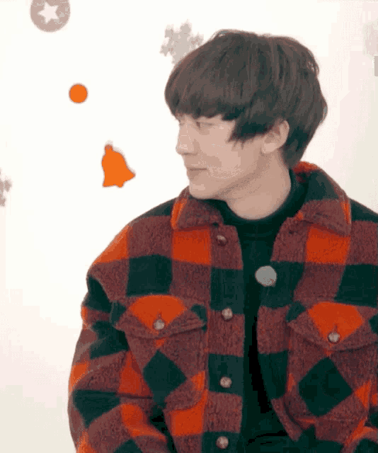 a young man wearing a plaid jacket looks to his left