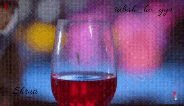 a glass of red wine is sitting on a table with a blurred background .