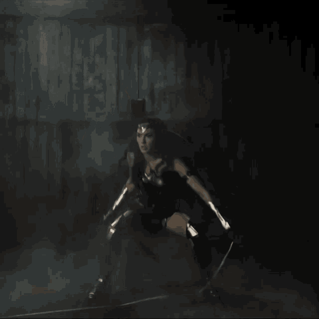 a woman is holding a shield in her hands in a dark room