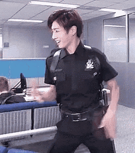a man in a police uniform is dancing in an office while holding a gun .