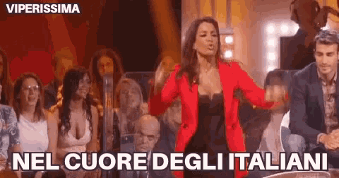 a woman in a red jacket is dancing on a stage in front of a crowd of people .
