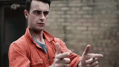 a man in an orange jacket is making a funny face and pointing at the camera .