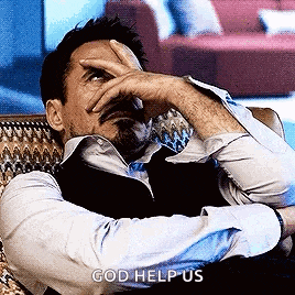 a man is sitting on a couch and covering his face with his hand .