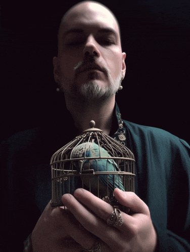 a man holding a bird cage with a blue bird inside of it