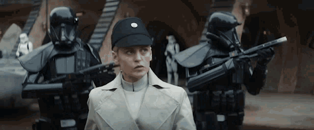 a woman in a white coat is standing in front of a group of stormtroopers .