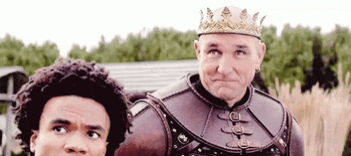a man with a crown on his head is standing next to a young man .