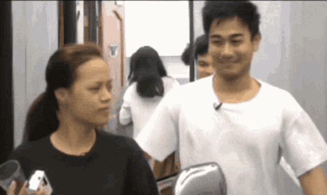 a man in a white shirt stands next to a woman