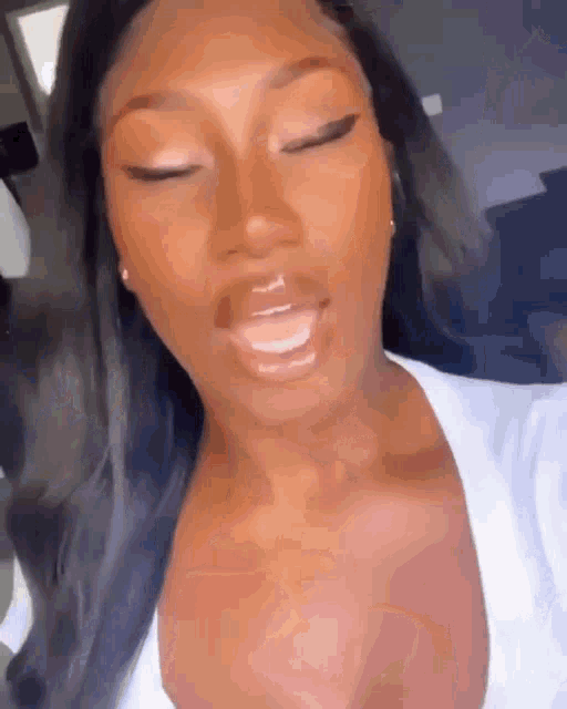 a close up of a woman 's face with her eyes closed and a white shirt on .