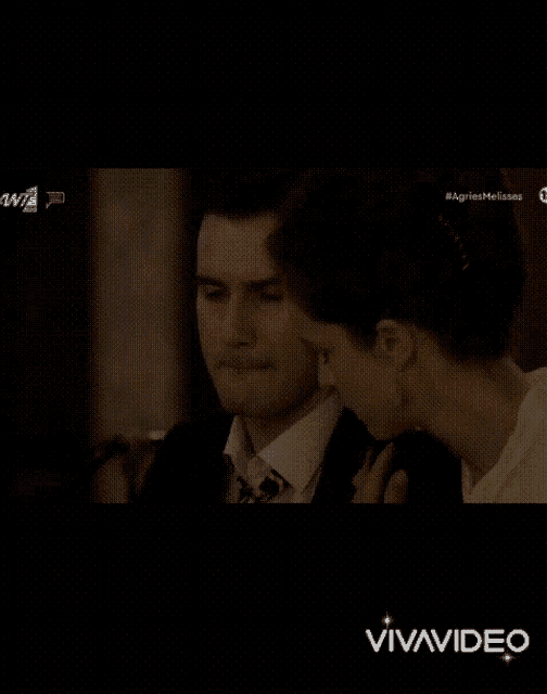 a man in a suit and tie is being kissed by a woman in a white shirt .