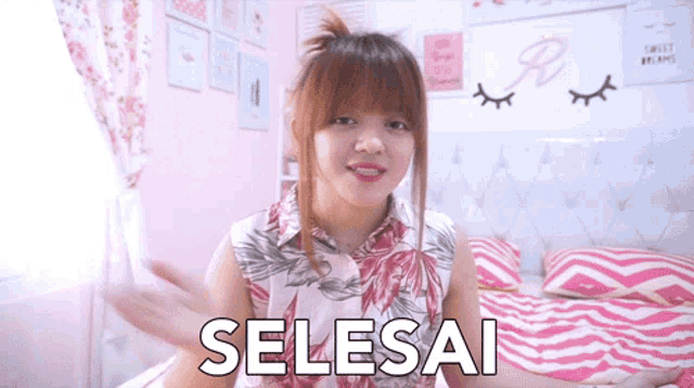 a woman is sitting on a bed with the word selesai written on the bottom