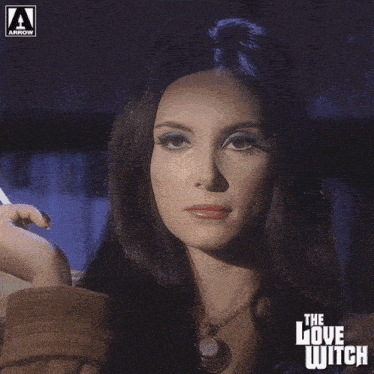 a woman is smoking a cigarette with the love witch written on the bottom