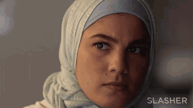 a close up of a woman wearing a hijab with the word slasher in the corner