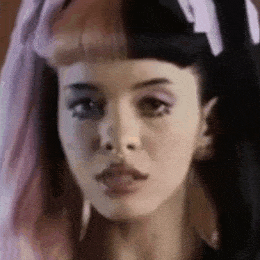 a close up of a woman 's face with two different colored hair .
