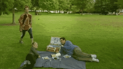 a group of people are having a picnic in a park with a dog .