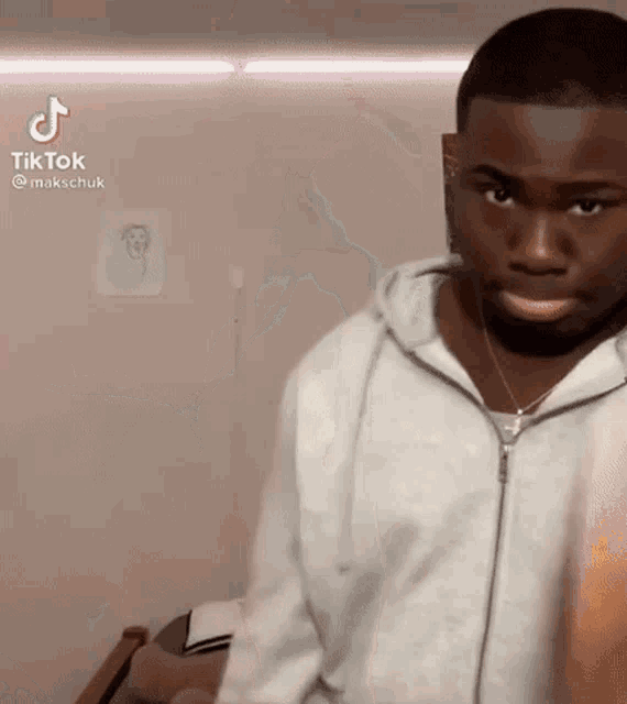 a young man in a white hoodie is standing in a room .