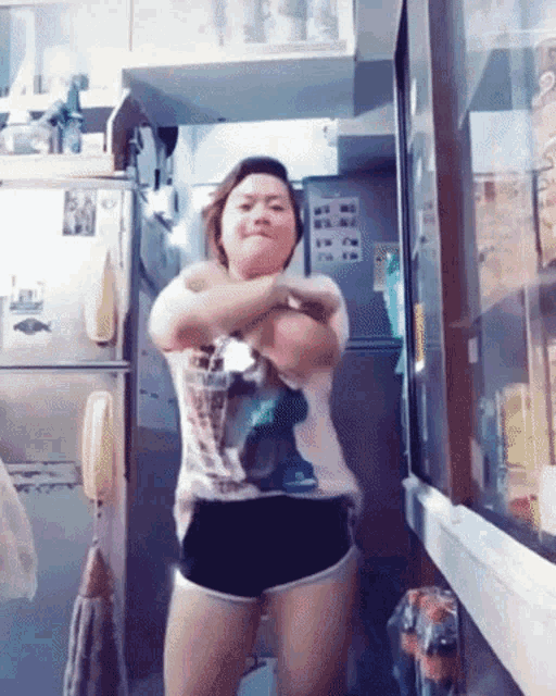 a woman is dancing in front of a refrigerator with a picture of a fish on the door