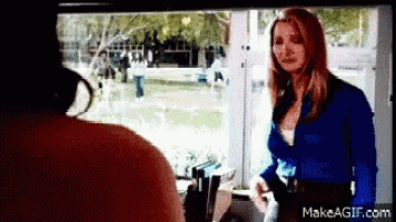 a woman in a blue shirt is standing in front of a window