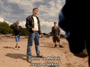 a man in a leather jacket stands in a dirt field with the words senar ve melek kavga ederken written below him