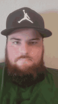 a man with a beard is wearing a black hat with the letter a on it
