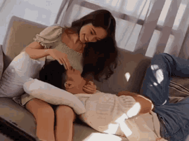 a man and a woman are laying on a couch .