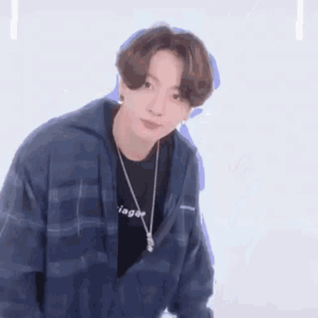 jungkook is wearing a blue plaid shirt and a black t-shirt .