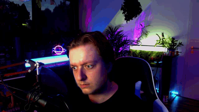 a man sitting in front of a microphone with a neon sign in the background that says planet