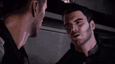 two men are looking at each other in a dark room