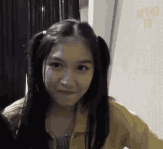 a girl with pigtails is wearing a yellow jacket and smiling ..