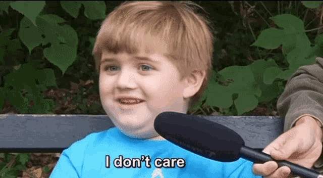 a little boy is sitting on a bench with a microphone and says i don 't care .