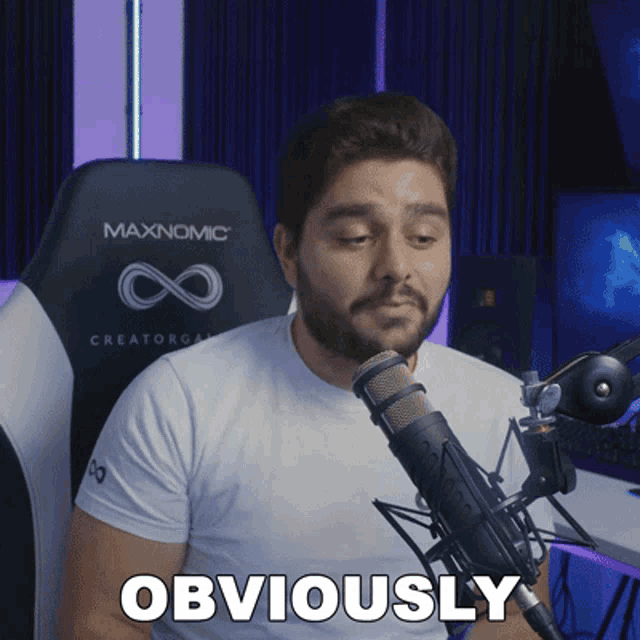 a man sitting in front of a microphone with obviously written on the bottom