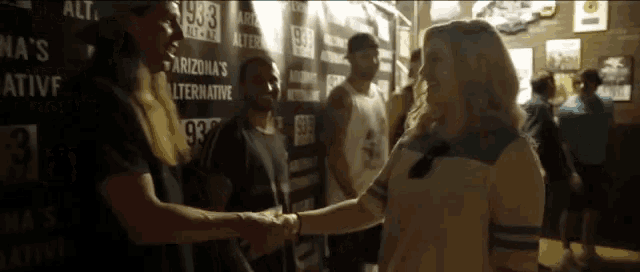 a woman shakes hands with a man in front of a sign that says 93.3
