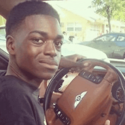 a young man is sitting in the driver 's seat of a car .