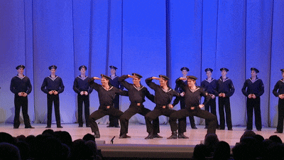 a group of men in navy uniforms are performing on stage