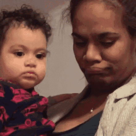 a woman is holding a baby in her arms and making a face .