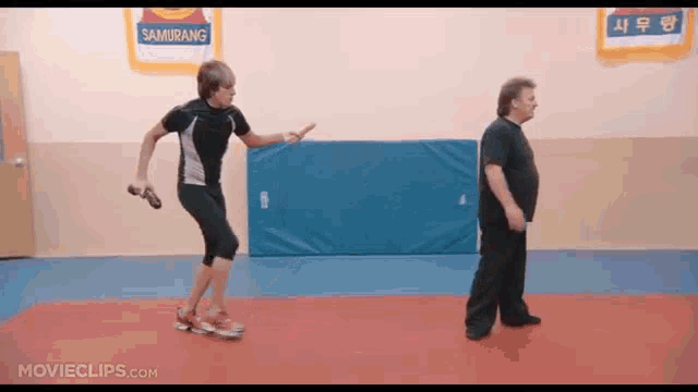 two men are standing in a gym with a sign that says samurang on it