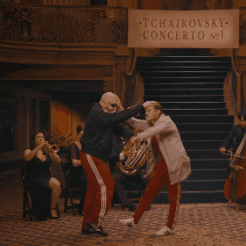 two men are dancing in front of a sign that says tchaikovsky concerto no. 1